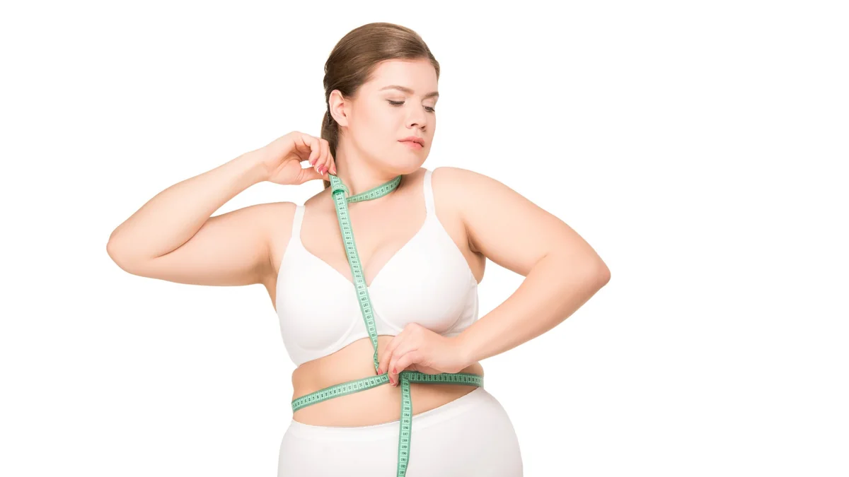 Person holding a measuring tape around their waist against a white background